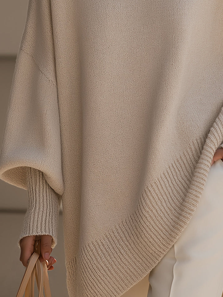 Detail des gerippten, schräg verlaufenden Saums und der engen Ärmelbündchen am beigen Strickponcho 4