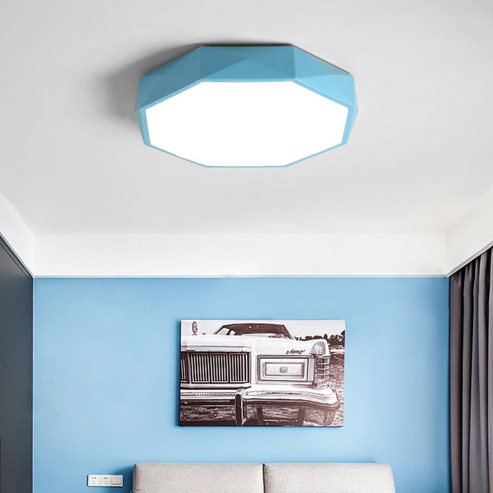 Blaue facettierte Deckenleuchte in einem Zimmer mit blauer Wand und Sofa darunter 3