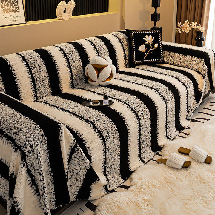 Sofa mit breit gestreiftem Bezug in Schwarz und Creme, dazu Kissen mit Blütenmotiv und flauschiger Teppich 9