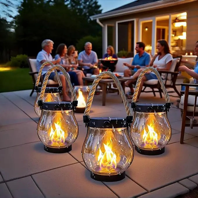Mehrere Laternen mit Wassertropfen auf dem Glas stehen auf einer Terrasse, im Hintergrund sitzt eine gesellige Runde 5