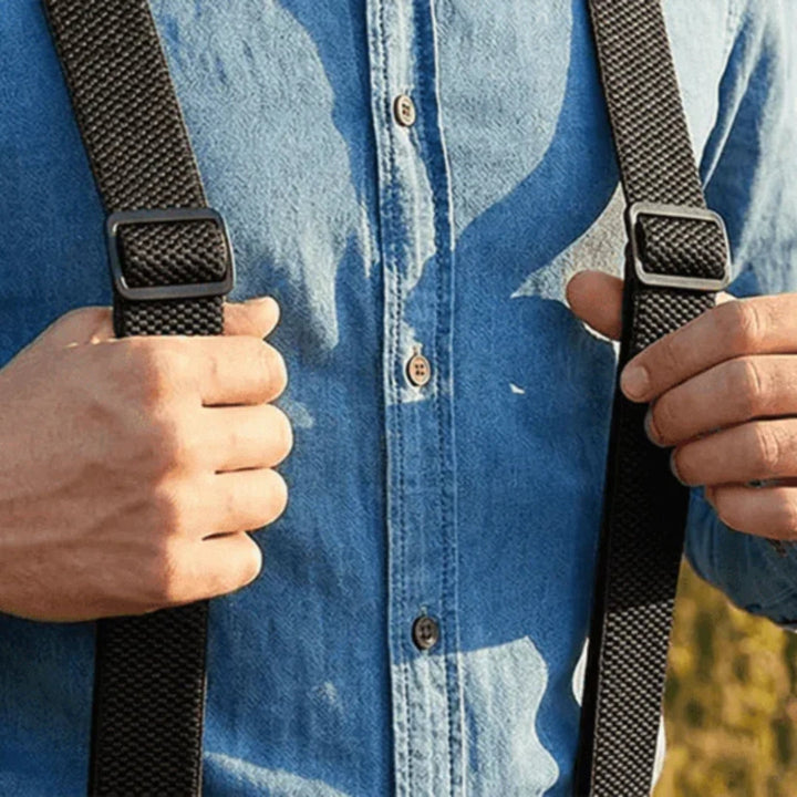 Nahaufnahme zweier schwarzer Hosenträgergurte mit Verstellschnallen auf einem blauen Jeanshemd, von Händen gehalten 18