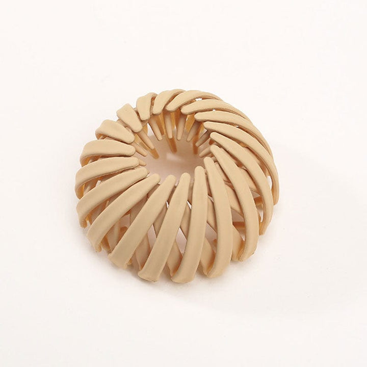 Einzelne matte Klammer in Sandbeige mit spiralförmigen Streben und leicht orangefarbenem Inneren, auf hellem Hintergrund. 10