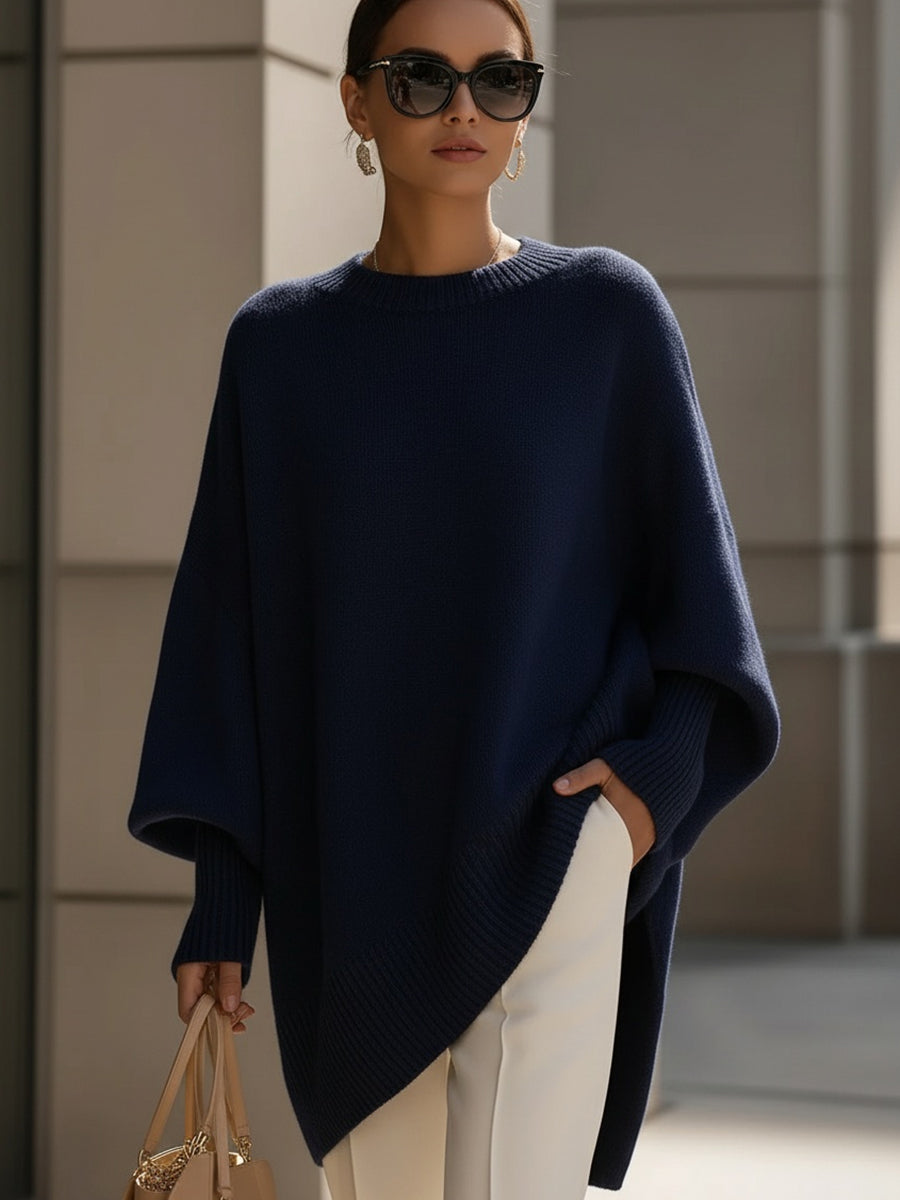 Dunkelblauer Strickponcho an einer Frau mit Sonnenbrille, weißer Hose und Handtasche 9