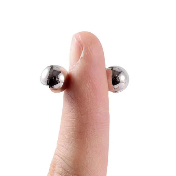 Daumenspitze, an der zwei silberfarbene Magnetkugeln auf gegenüberliegenden Seiten haften und so die Haftkraft zeigen. 7