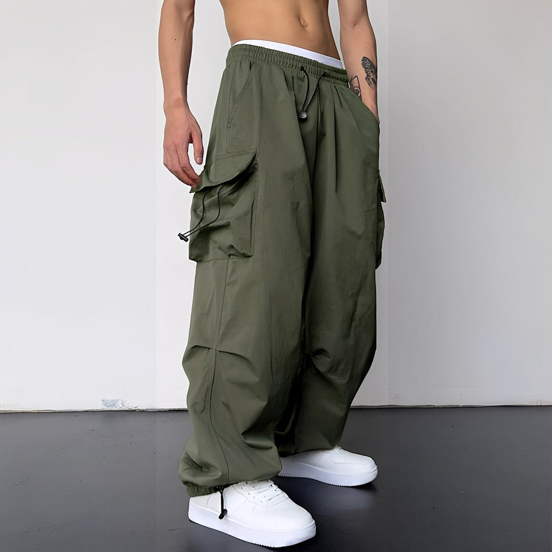 Dieselbe weite Cargohose in Olivgrün, am Model mit weißen Sneakern, Seitentaschen und Kordelzügen sichtbar 2