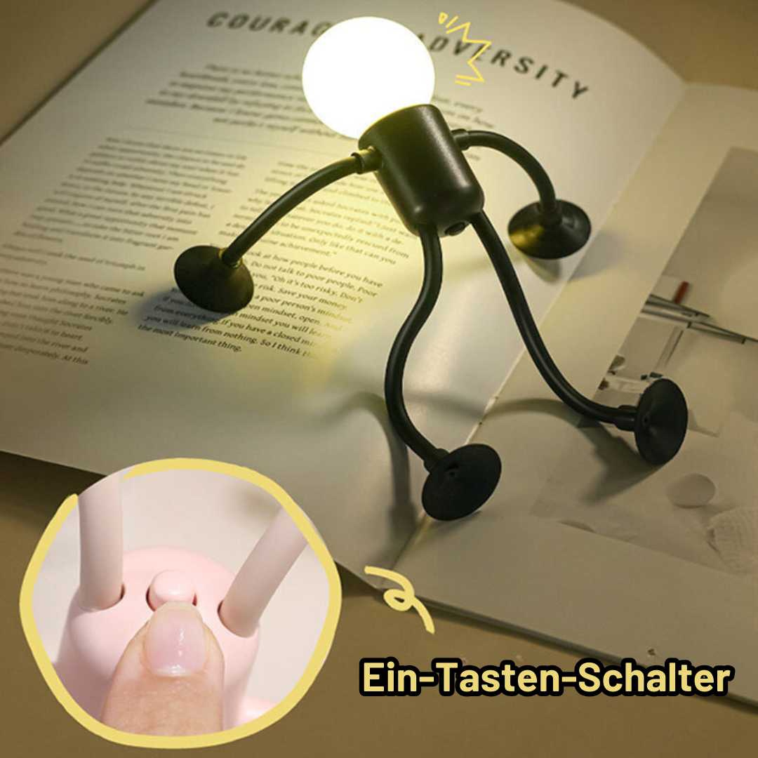 Schwarze Figurenlampe steht auf einem aufgeschlagenen Buch und beleuchtet die Seiten; Ausschnitt zeigt den Schalter am Körper einer rosa Lampe. 10