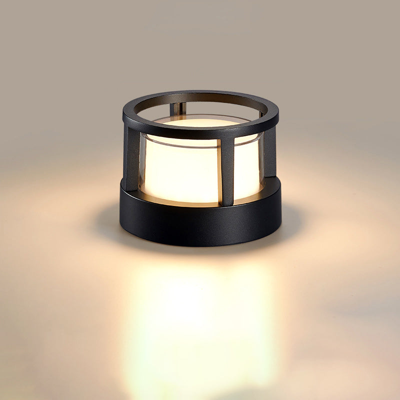 Runde schwarze Leuchte mit offenem Ringrahmen statt Deckel, der Lichtzylinder ist von oben sichtbar, warmes Licht im Hintergrund. 9