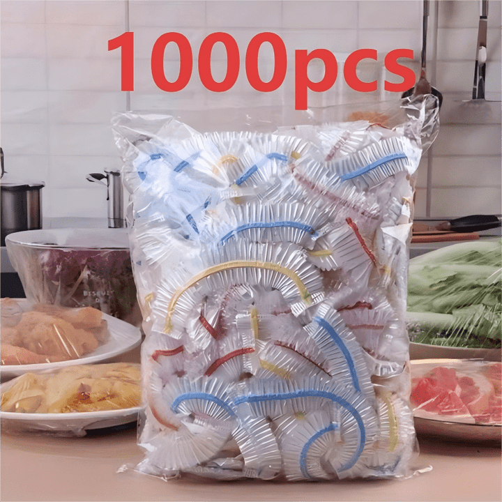 Beutel mit farbig gesäumten Abdeckungen auf einer Küchenarbeitsplatte, dahinter abgedeckte Schalen mit Salat, Fleisch und Nudeln. 3
