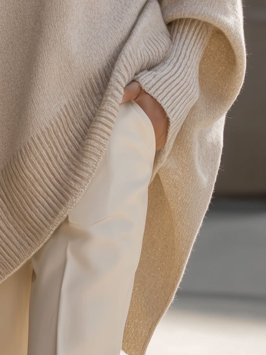 Seitliches Detail mit Hand in der Hosentasche, gerippter Saum und seitlicher Schlitz des beigen Ponchos 6