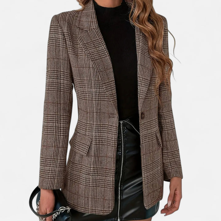 Frontansicht des karierten Blazers an einem Model, getragen zu schwarzem Rollkragenoberteil und schwarzem Lederrock, mit Knopf und Klappentaschen. 1
