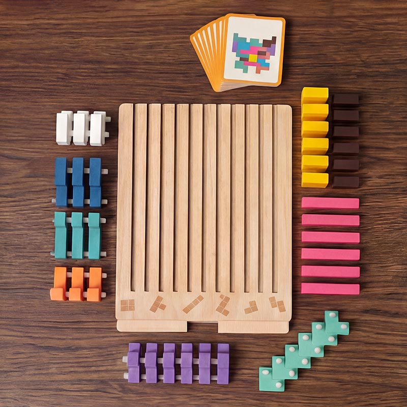 Draufsicht auf dem Holztisch: Spielbrett mit Schlitzen, alle Bausteine nach Farben sortiert und ein Stapel Vorlagekarten. 2