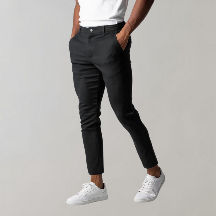 Schwarze Chinohose für Herren, Slim Fit, Baumwolle, elegant, modern, mit weißen Sneakern.