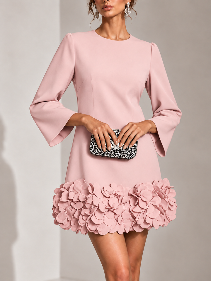 Rosafarbenes Kleid in Frontansicht mit Rundhals, ausgestellten Ärmeln und dichtem Blütenbesatz am Saum, dazu Strass-Clutch. 9