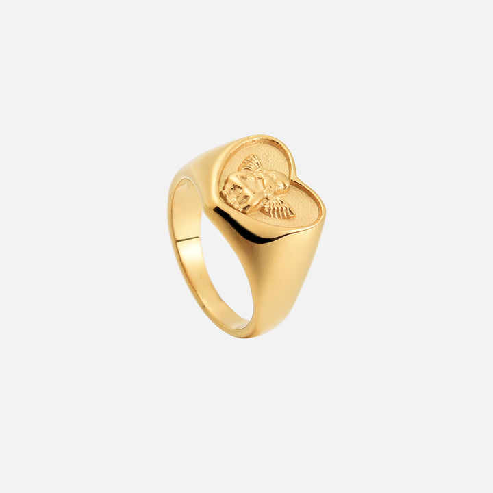 Dasselbe goldfarbene Herzring-Modell von oben schräg fotografiert, mit Blick auf die Ringschiene und das Engelrelief. 2