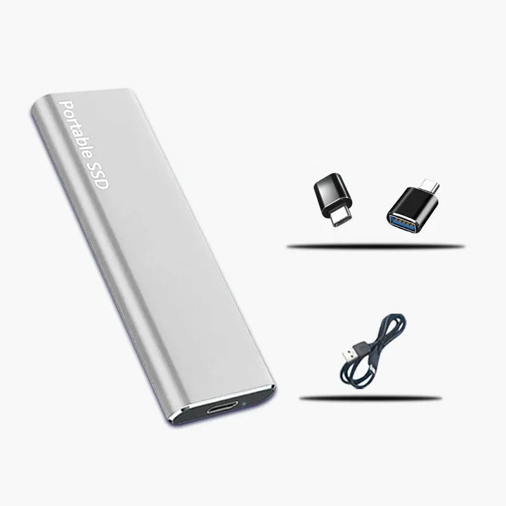 Silberfarbene Festplatte neben zwei schwarzen USB-Adaptern und einem dunklen USB-Kabel, die als Zubehör mitgeliefert werden. 2