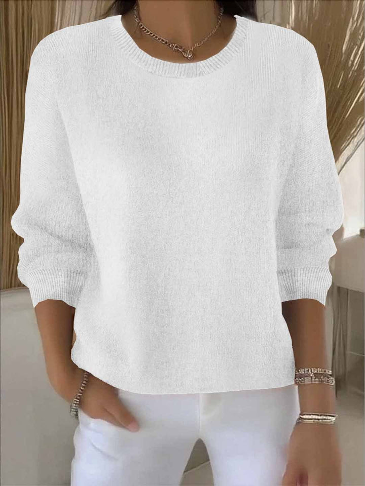 Weiße Variante des Strickpullovers mit gerippten Bündchen, vom Model zu weißer Hose und Armbändern getragen 3