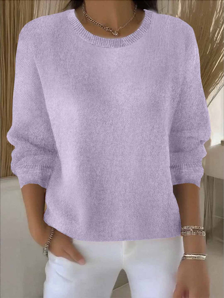 Fliederfarbene Variante des Strickpullovers, Frontansicht am Model mit Rundhals, gerippten Bündchen und weißer Hose 14