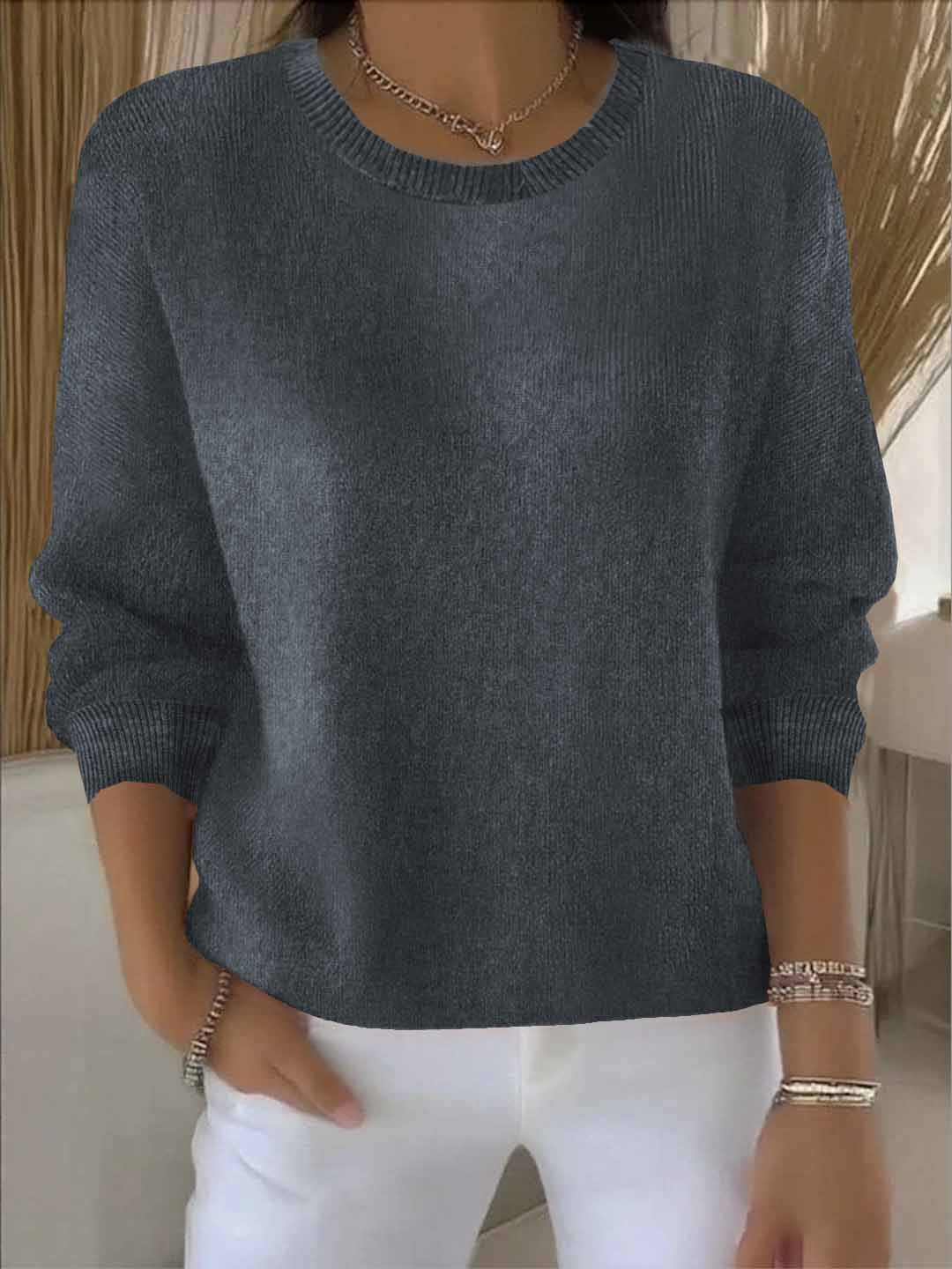 Dunkelgraue Variante des Strickpullovers in Frontansicht, mit gerippten Bündchen, vom Model zu weißer Hose getragen 6