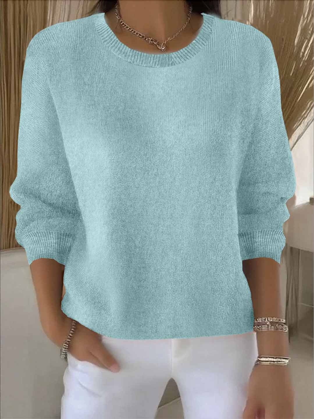Hellblaue, leicht türkisfarbene Variante des Strickpullovers, vom Model zu weißer Hose und Armbändern getragen 10