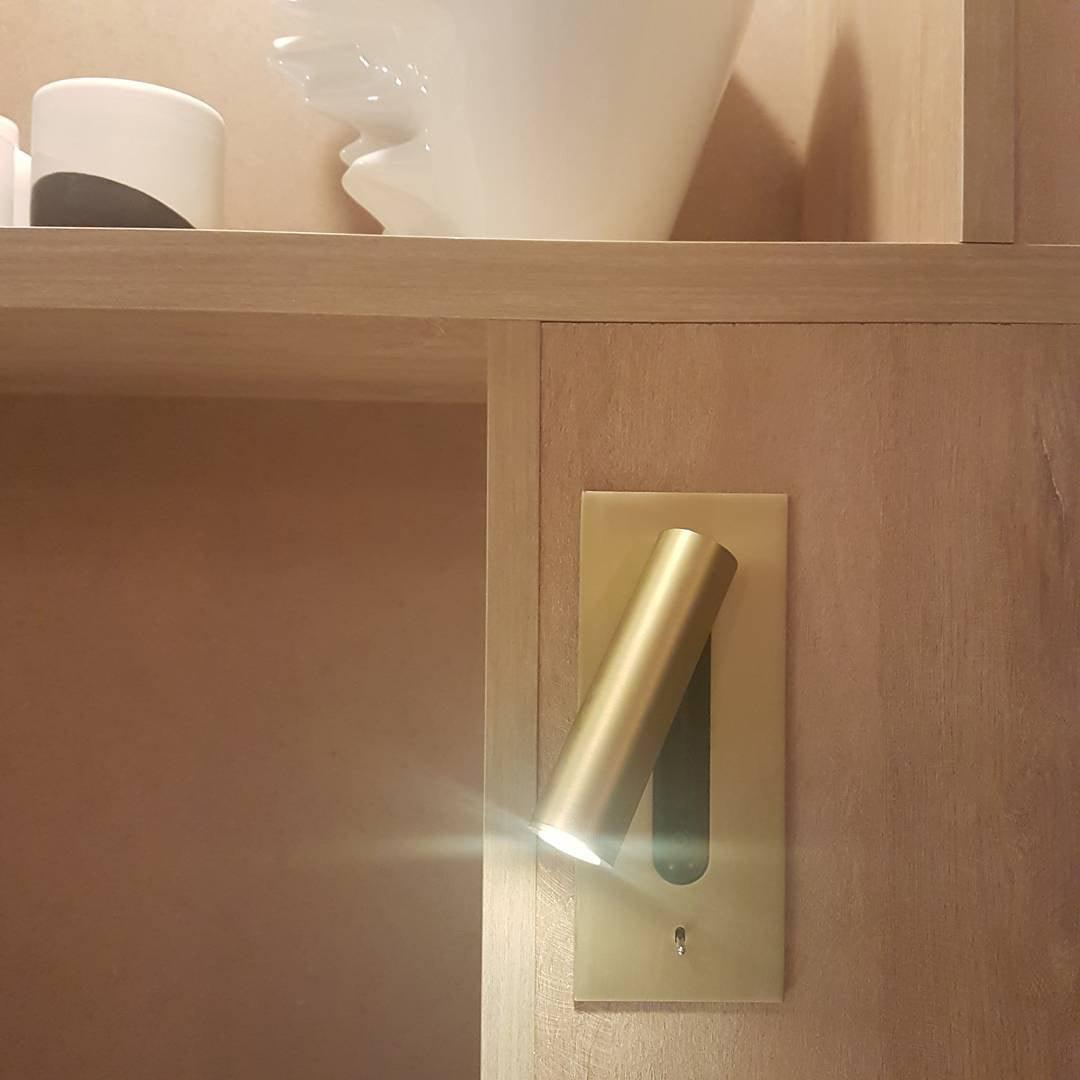 Goldfarbene Wandleuchte in Holzregal eingebaut, der Lichtkegel strahlt nach links 32