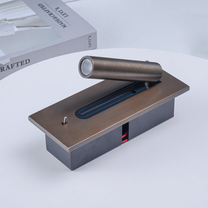 Leuchte liegend auf weißem Tisch, dunkle Einbaubox mit rotem Kabel sichtbar, Strahler mit Linse, Kippschalter, Buch im 13
