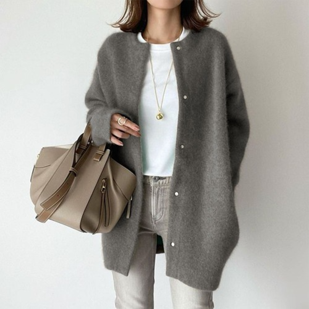 Frau trägt die flauschige Strickjacke in Grau mit Druckknöpfen, weißem Shirt und heller Jeans 6