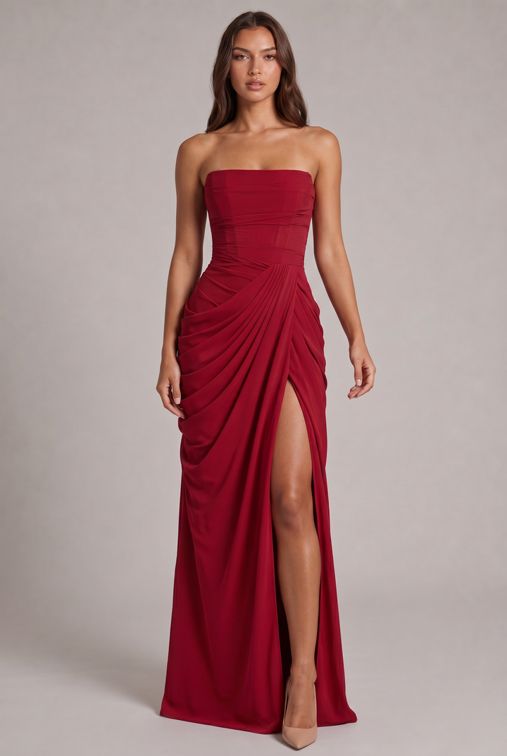 Rotes Kleid in der Frontansicht: Model mit gerafftem Wickelrock, Corsagenoberteil und hohem Beinschlitz, dazu nudefarbene 21