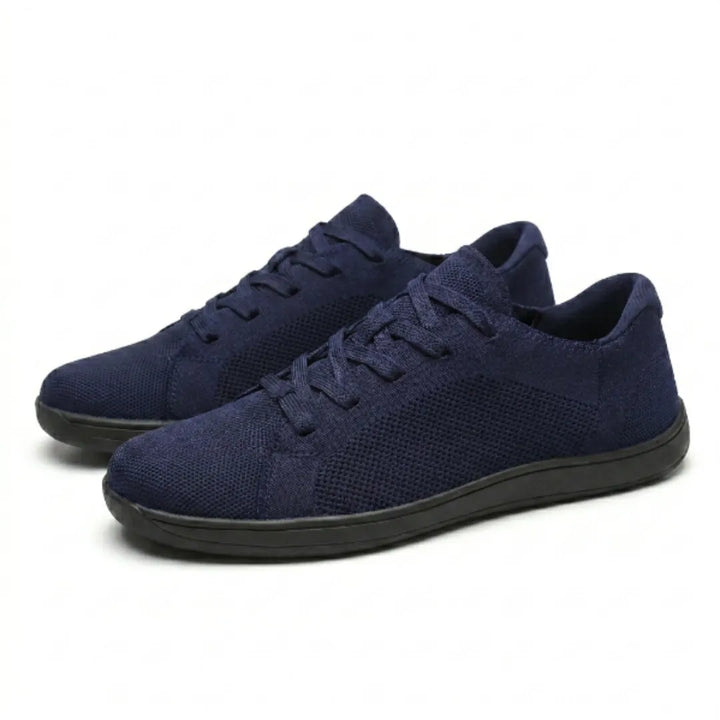 Paar marineblaue Barfuß-Sneaker aus Mesh mit schwarzer flacher Sohle und Schnürung, schräg von vorne auf weißem Hintergrund. 25