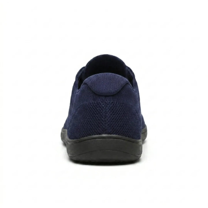 Rückansicht eines marineblauen Mesh-Sneakers mit gepolsterter Fersenkappe und flacher schwarzer Sohle. 27