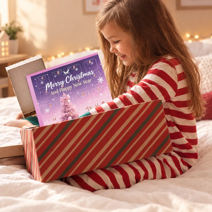 Mädchen im rot-weiß gestreiften Schlafanzug sitzt auf dem Bett und zieht lächelnd einen violett-rosa Adventskalender mit nummerierten Türchen aus einer gestreif 3