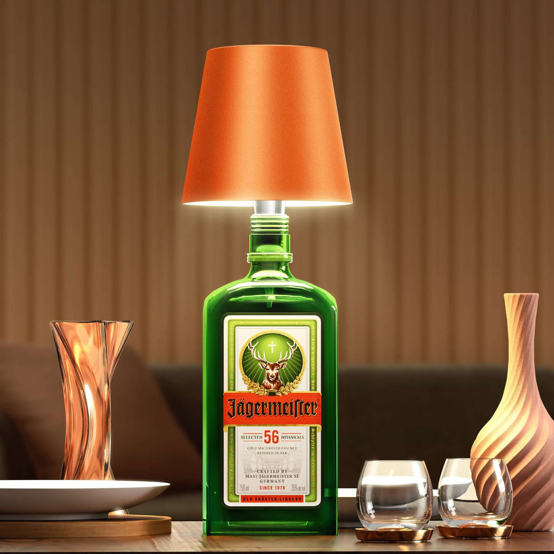 Grüne Jägermeister-Flaschenlampe mit orangefarbenem Schirm auf Holztisch, moderne Dekoration.