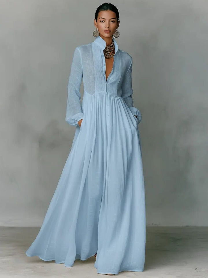 Maxikleid in Hellblau, ganze Frontansicht am Model mit Statement-Kette und Händen in den Taschen 3