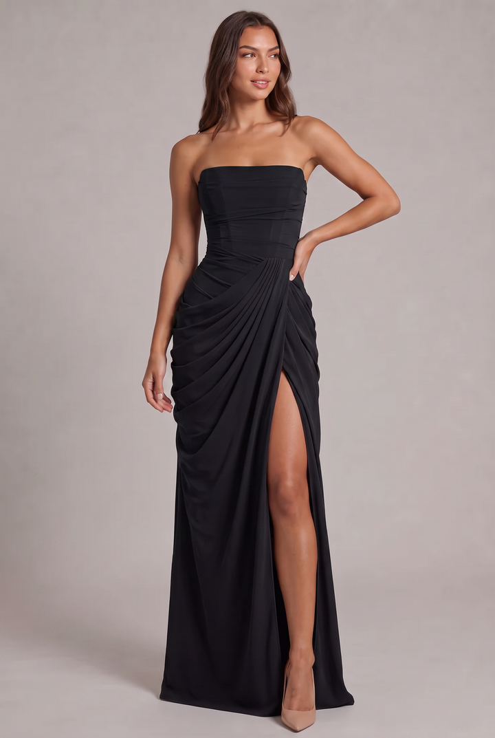 Schwarzes Kleid in der Frontansicht: Model mit Hand an der Hüfte, drapiertem Rock, Corsagenoberteil und hohem Schlitz 25