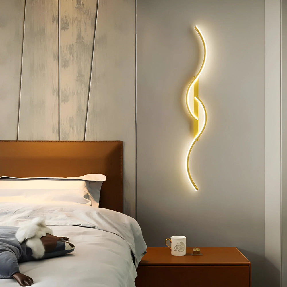 Goldene Wandleuchte mit Wellenform leuchtet im Schlafzimmer neben Bett und Nachttisch 2