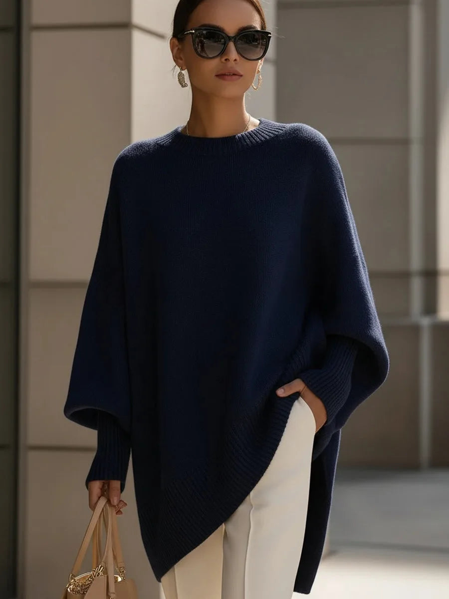 Dunkelblauer Pullover mit weitem Schnitt und asymmetrischem Saum, getragen von einer Frau mit Sonnenbrille und weißer Hose. 8