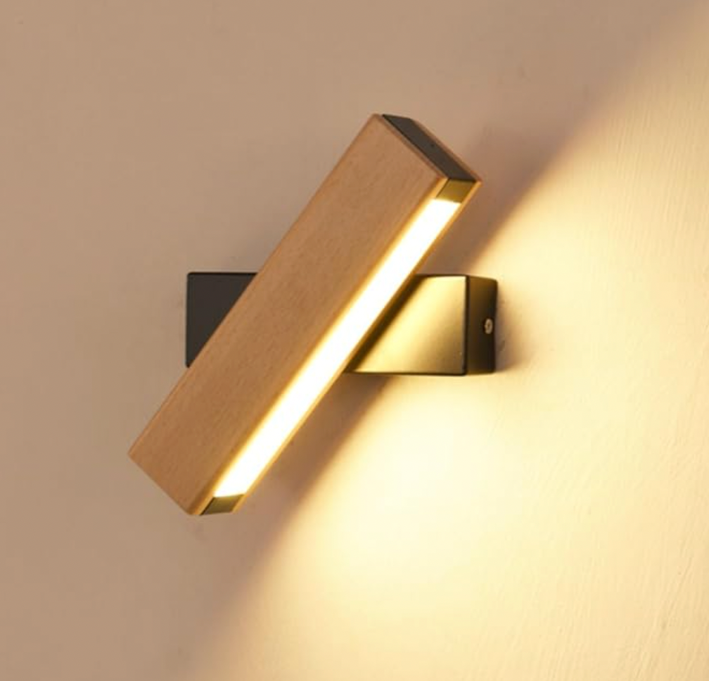 Nahaufnahme der leuchtenden Holzleiste mit schwarzer Wandhalterung, schräg gedreht, das Licht fällt warm auf die Wand. 7