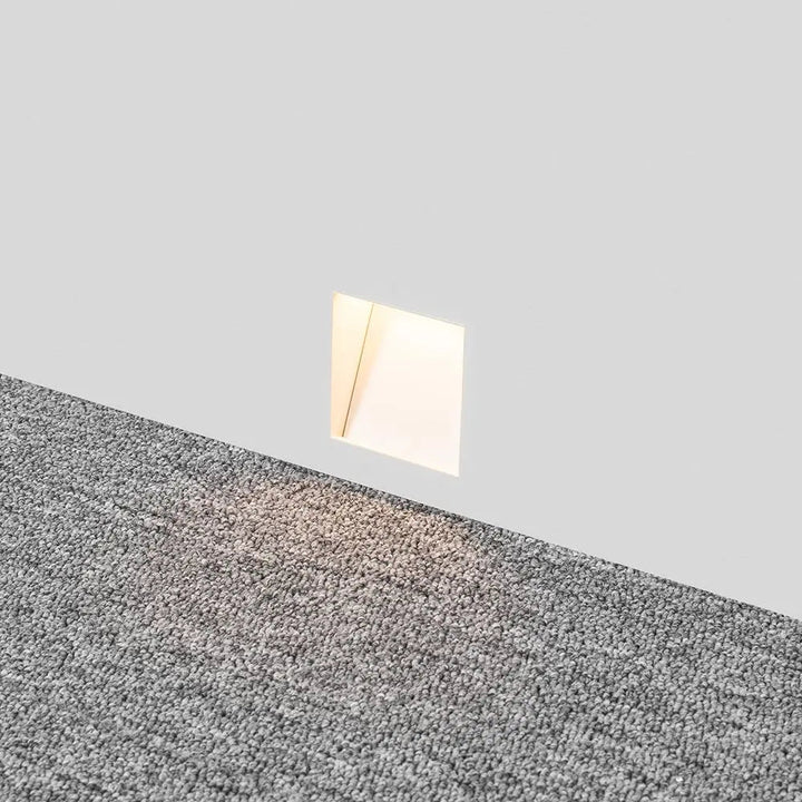 In die Wand eingebaute leuchtende Einbauleuchte über grauem Teppich, Licht fällt auf den Boden 3