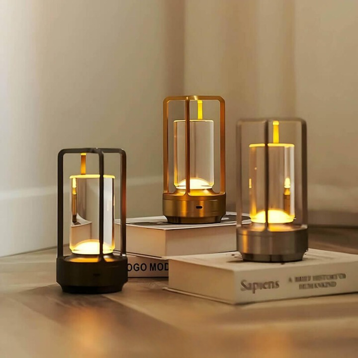 Drei Lampen in Schwarz, Gold und Silber stehen leuchtend auf aufgeschlagenen Büchern und einem Holzboden. 2