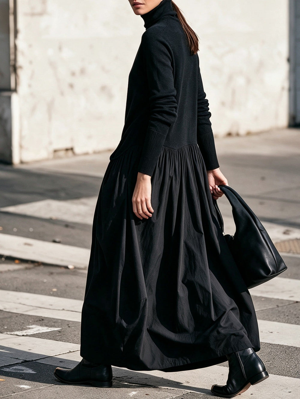 Seitenansicht in Schwarz: Model im Kleid mit gerafftem Rock auf der Straße, schwarze Handtasche in der Hand 2