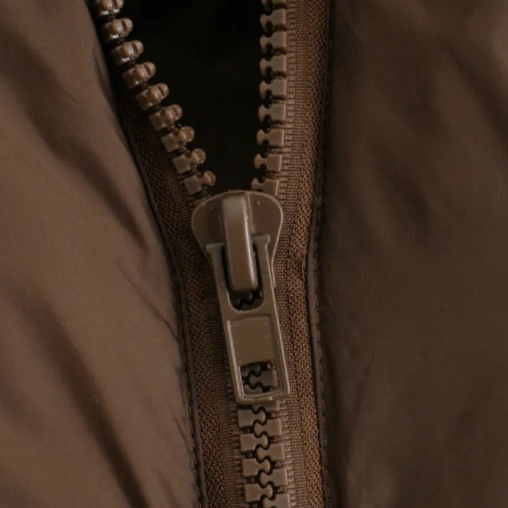 Brauner Reißverschluss aus Kunststoff auf Jacke, Nahaufnahme, Modeaccessoire, Detailansicht.