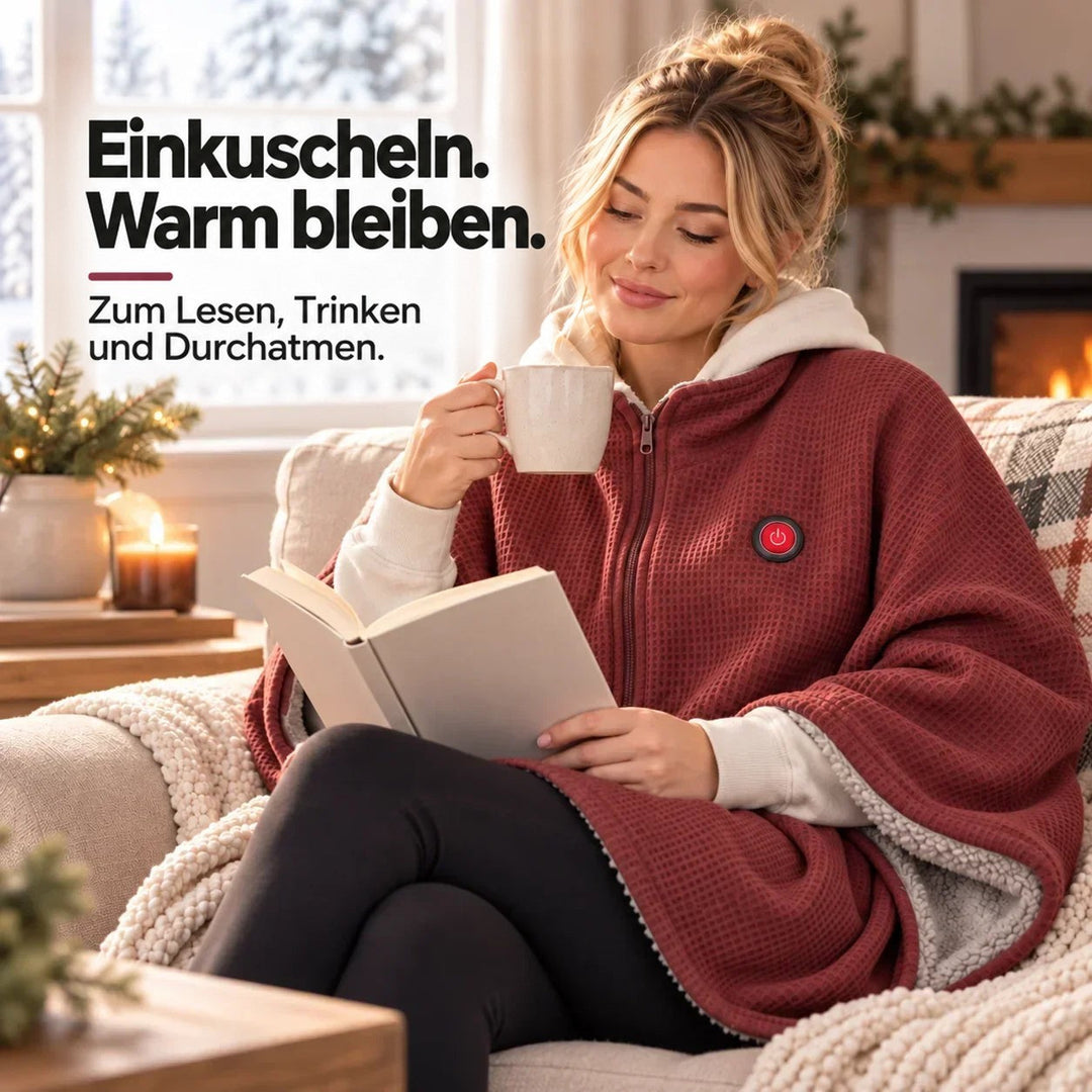 Frau liest mit Tasse am Kamin, trägt die rote Decke mit heller Kapuze 10