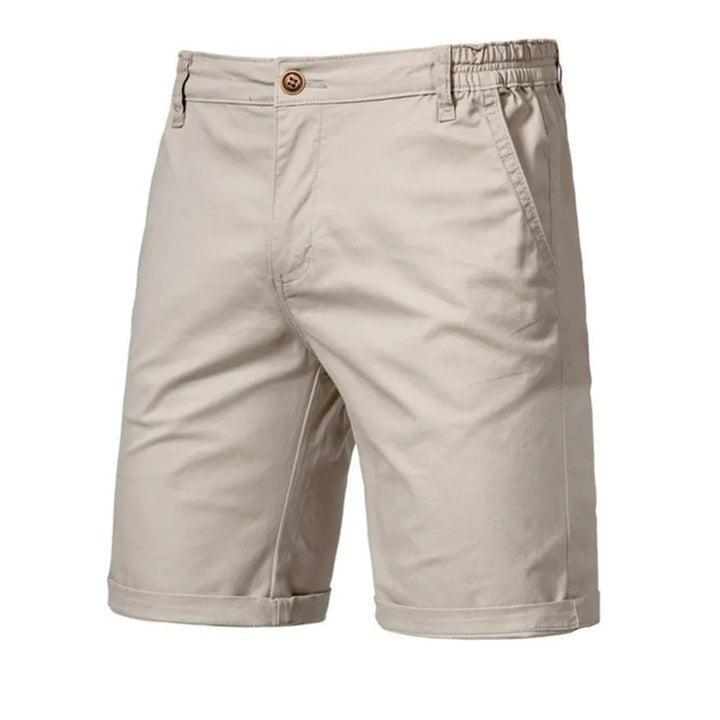 Beige Bermudashorts in der Vorderansicht mit Knopfverschluss, Gummizug seitlich am Bund, Eingrifftasche und umgeschlagenem Saum. 1