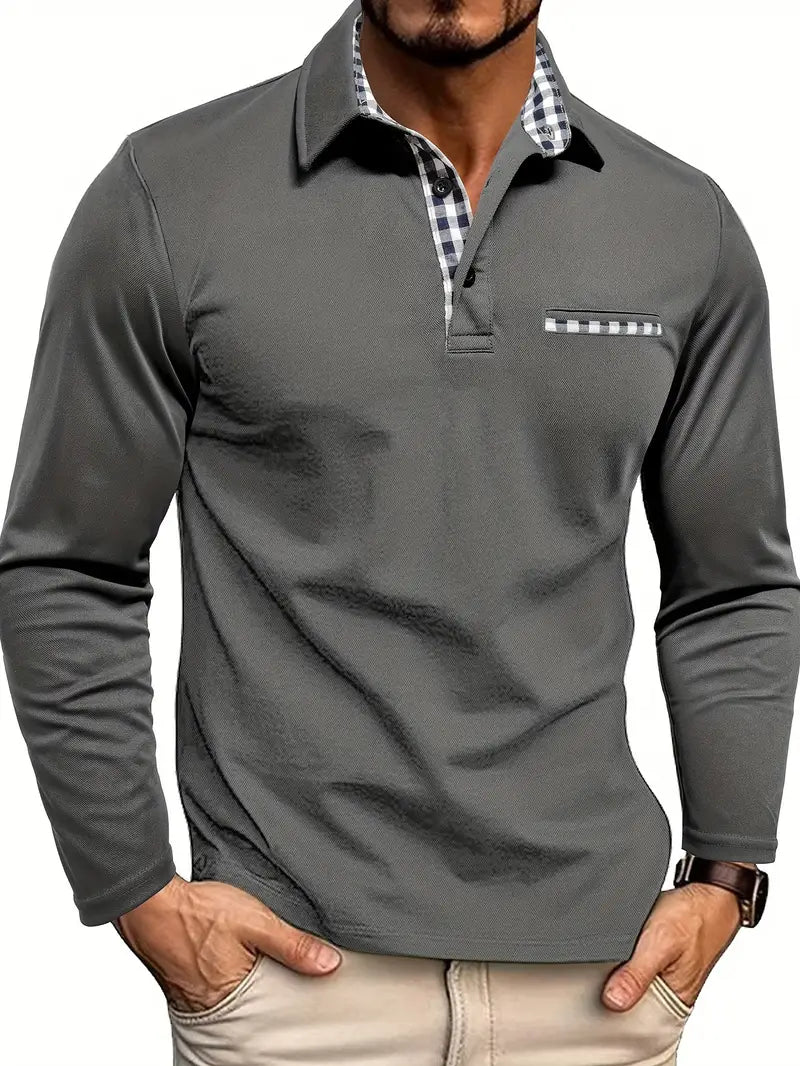 Mann trägt graues Langarm-Poloshirt mit Karo-Innenkragen und Karo-Brusttasche, Hände in den Hosentaschen 1