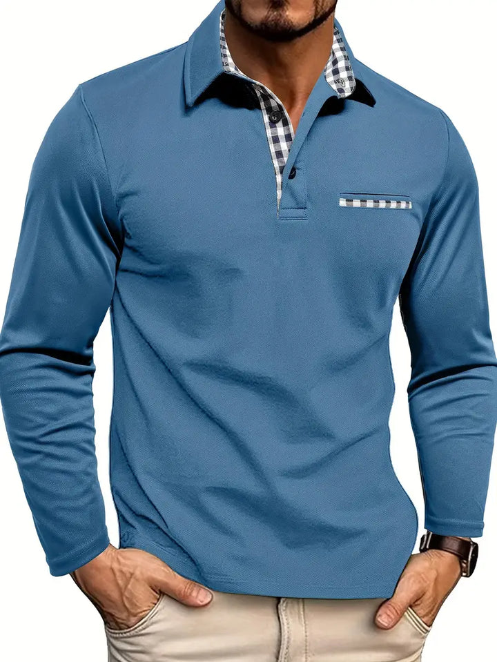 Mann trägt graublaues Langarm-Poloshirt mit Karodetails an Kragen und Brusttasche, Hände in den Hosentaschen 4