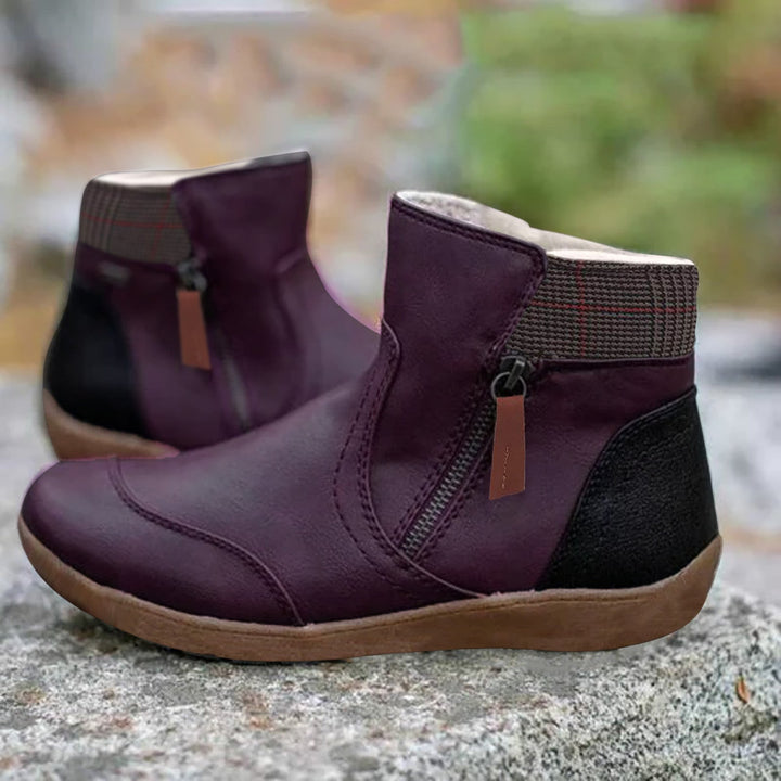 Dunkelviolette Stiefeletten mit schwarzer Ferse, Reißverschluss an der Seite und kariertem Schaftabschluss, auf einem Felsen im Freien. 4