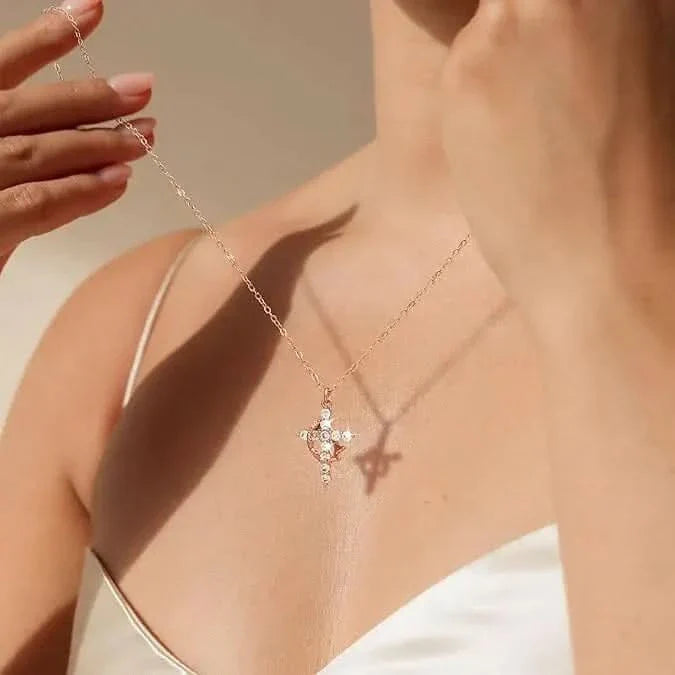Frau im weißen Trägertop hält die feine Kette mit dem Kreuzanhänger hoch, der auf ihrem Dekolleté einen Schatten wirft. 1