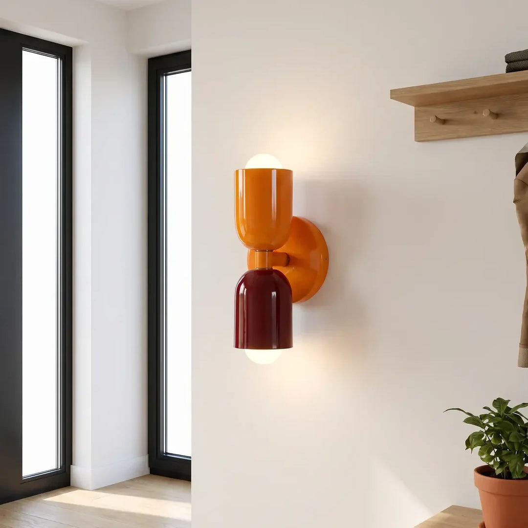 Wandlampe mit orangefarbenem oberem Schirm und Halterung sowie weinrotem unterem Schirm im Eingangsbereich neben einer Holz-Garderobe. 11