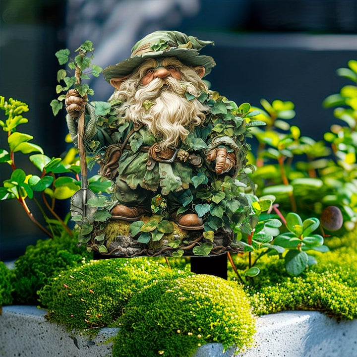 Gartenzwerg mit Spaten und Efeublättern auf einem Moospolster zwischen grünen Pflanzen, mit schwarzem Steckfuß. 13