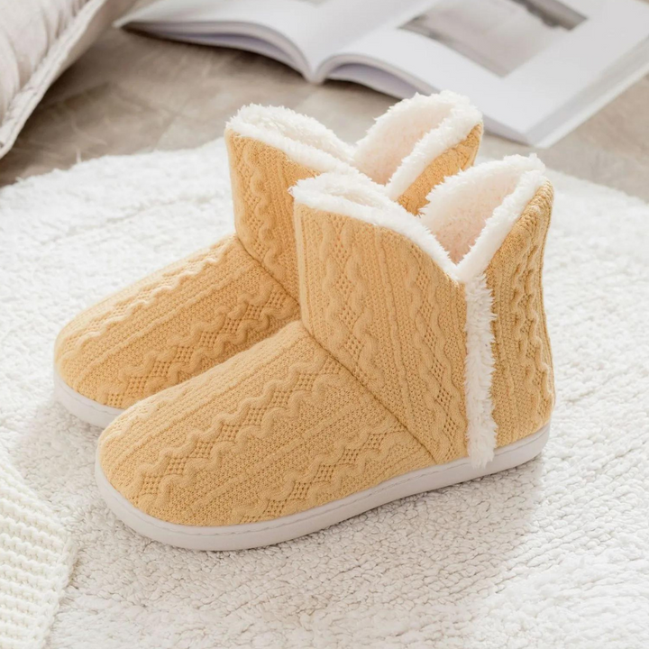 Gelbe Damen-Hausschuhe aus Strick mit Plüschfutter auf Teppich, gemütlich und warm.