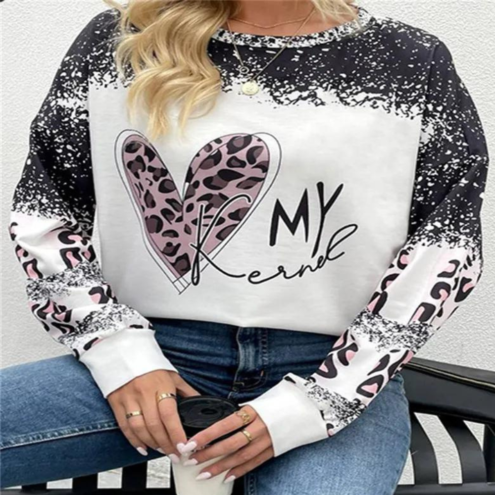 Frau trägt weißen Pullover mit Herz-Print und Leopardenmuster, lässige Mode, Kaffeetasse in Hand.